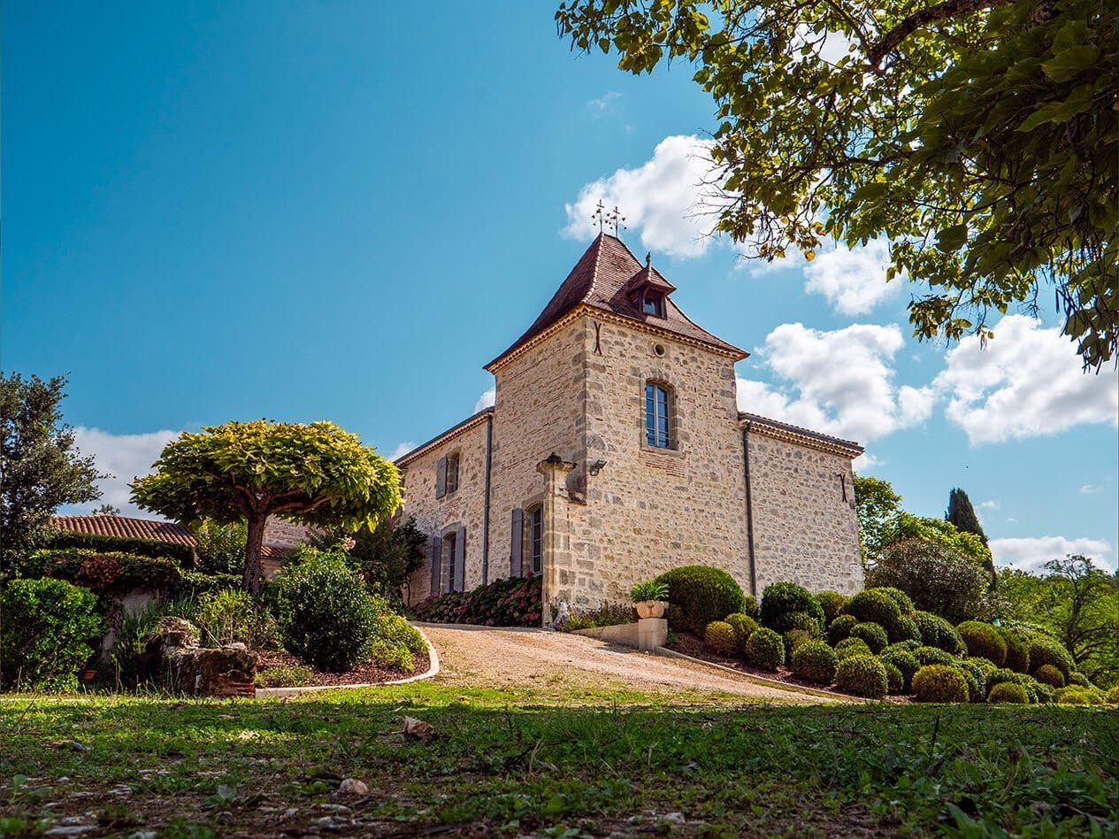 The tower and façade of Manoir Blanche Haut above the garden