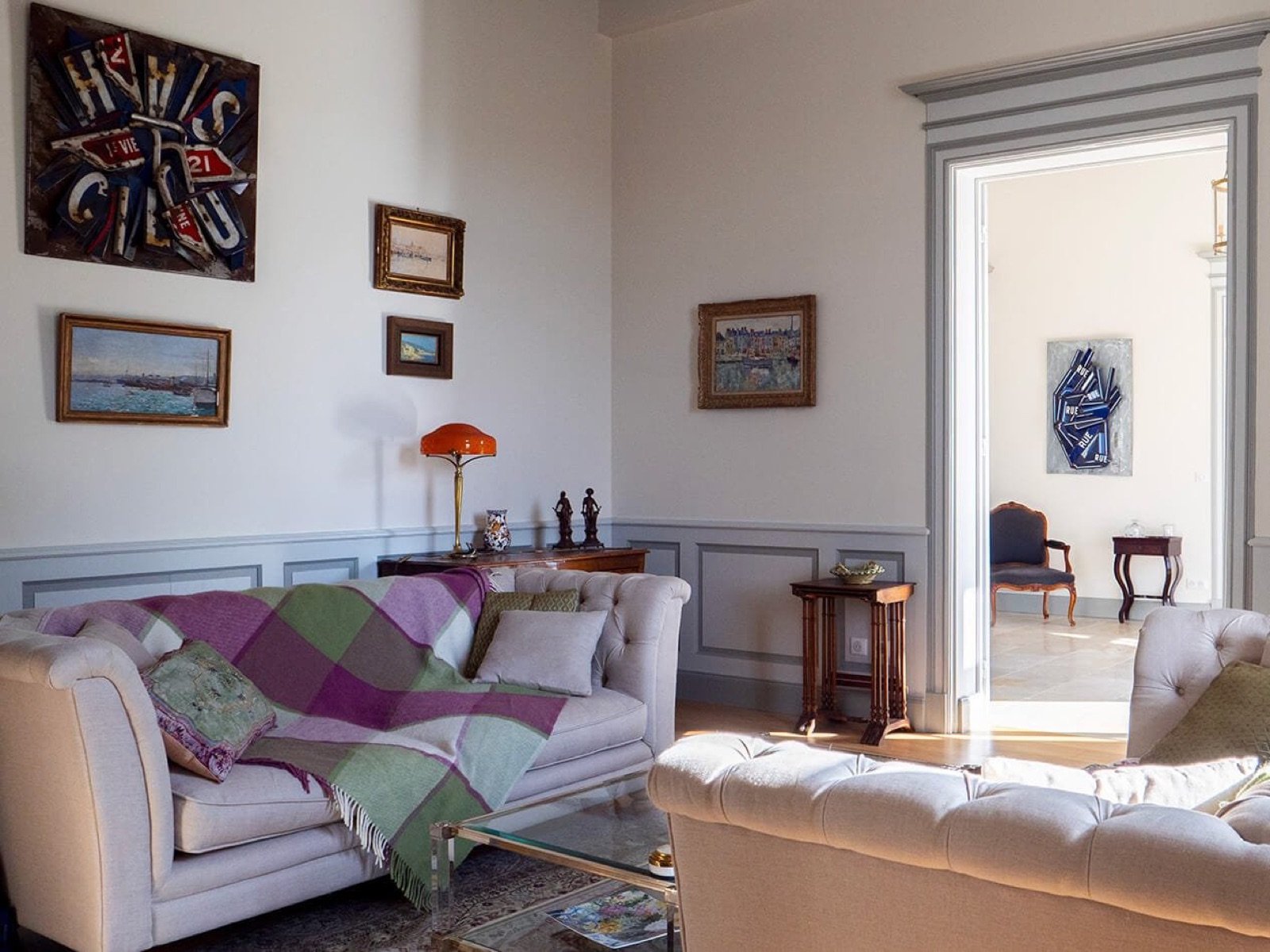The manor's grand salon: buttoned sofas, paintings and an antique lamp
