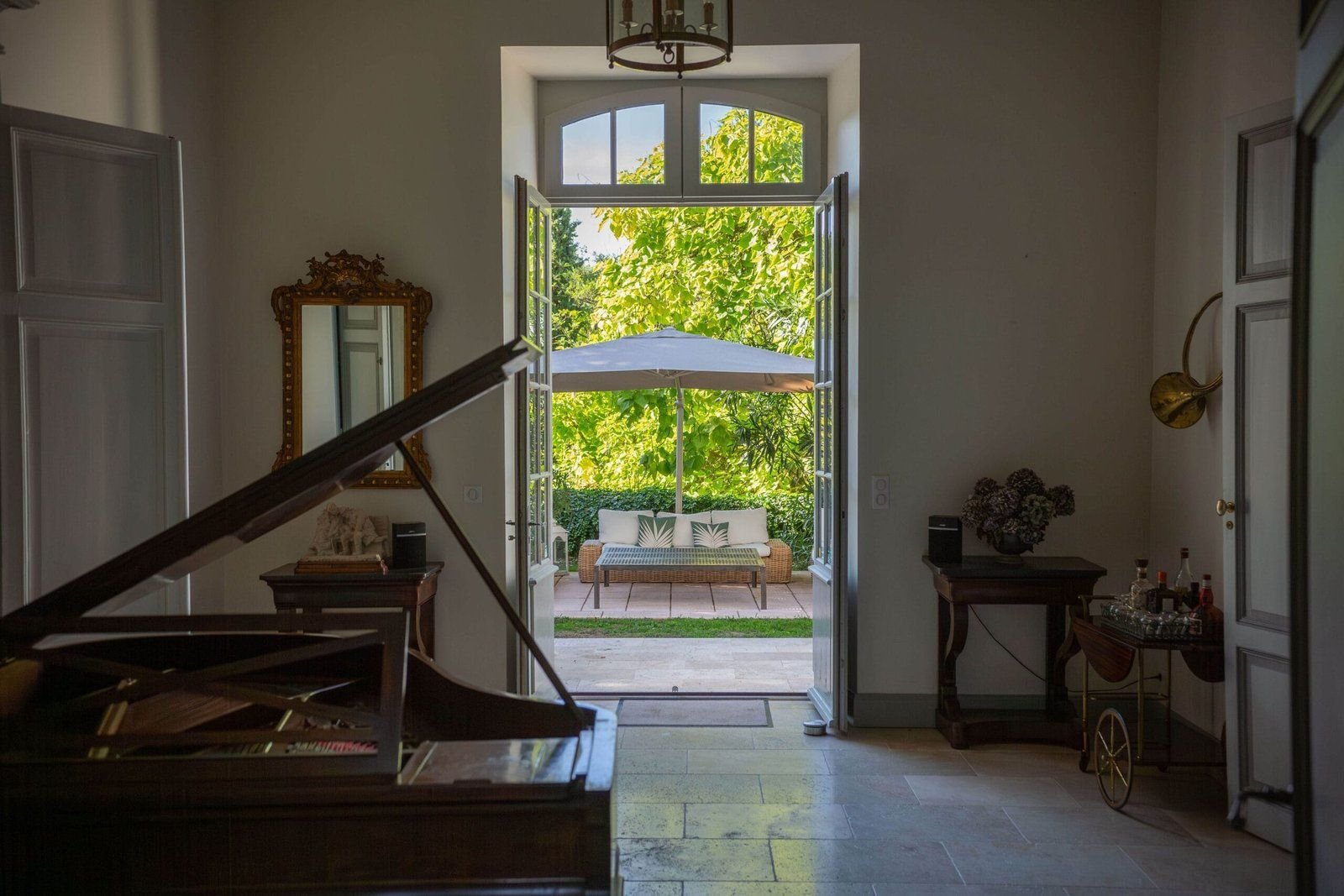 The salon and its grand piano, French windows open onto the garden