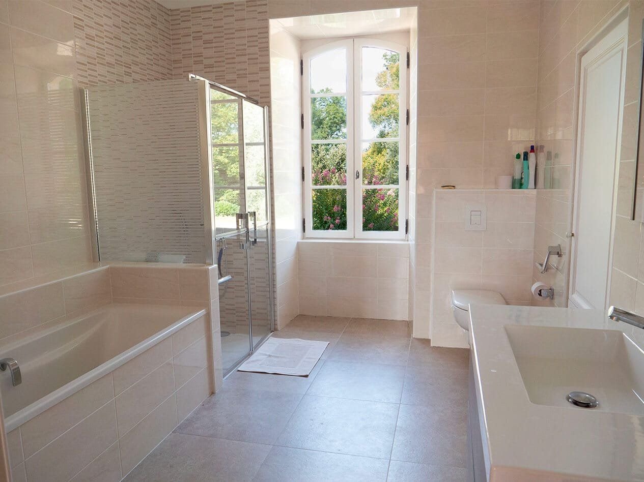 Salle de bain de La Jolie avec baignoire, douche à l'italienne et fenêtre