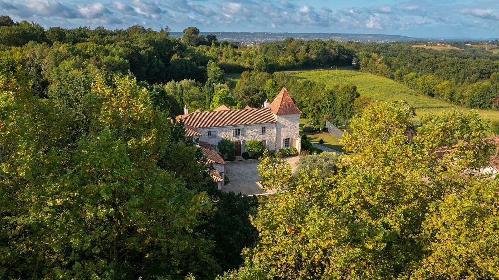 The manor in its ten-acre wooded park, with the Lot valley on the horizon