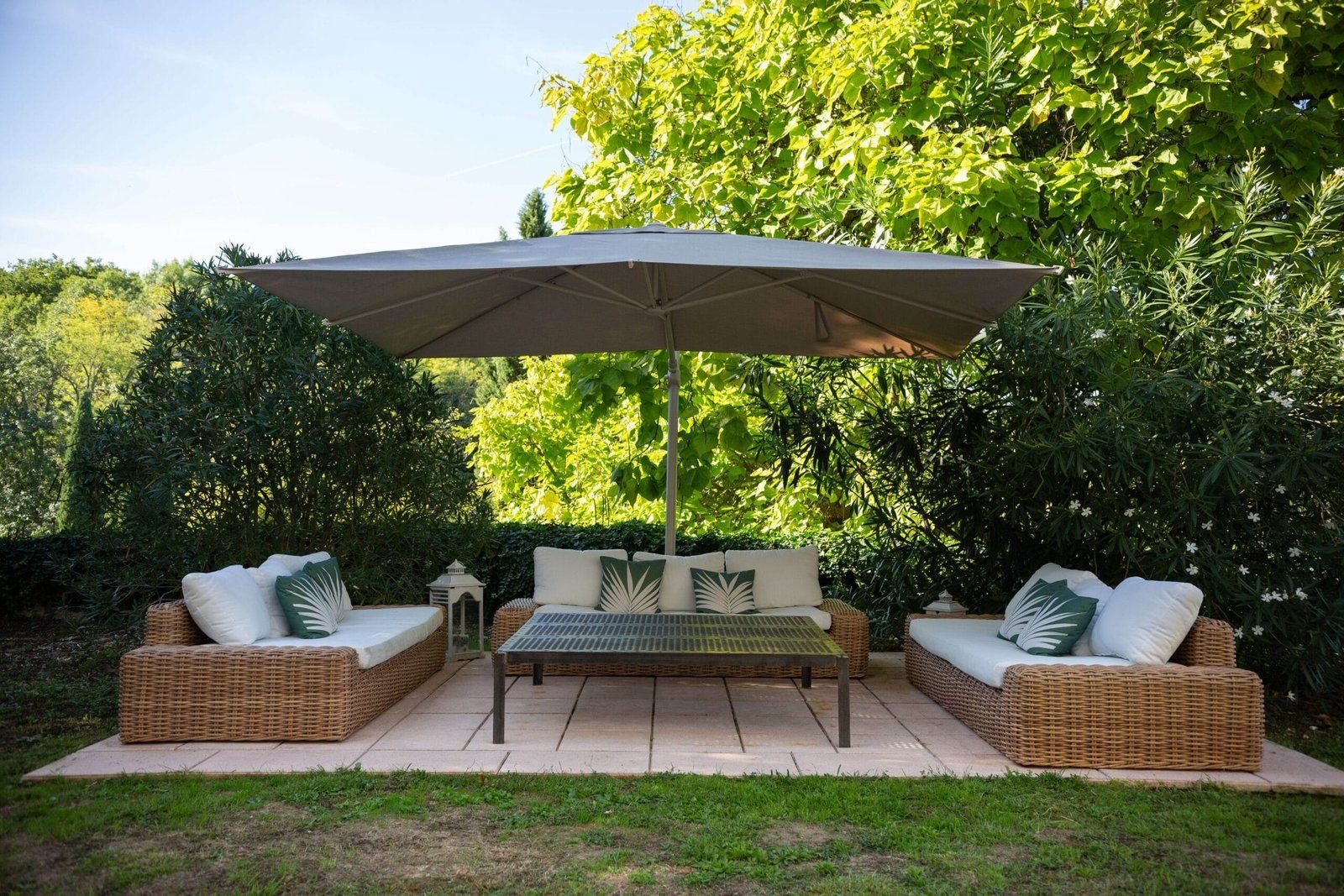 Salon de jardin à l'ombre d'un parasol, sur la pelouse